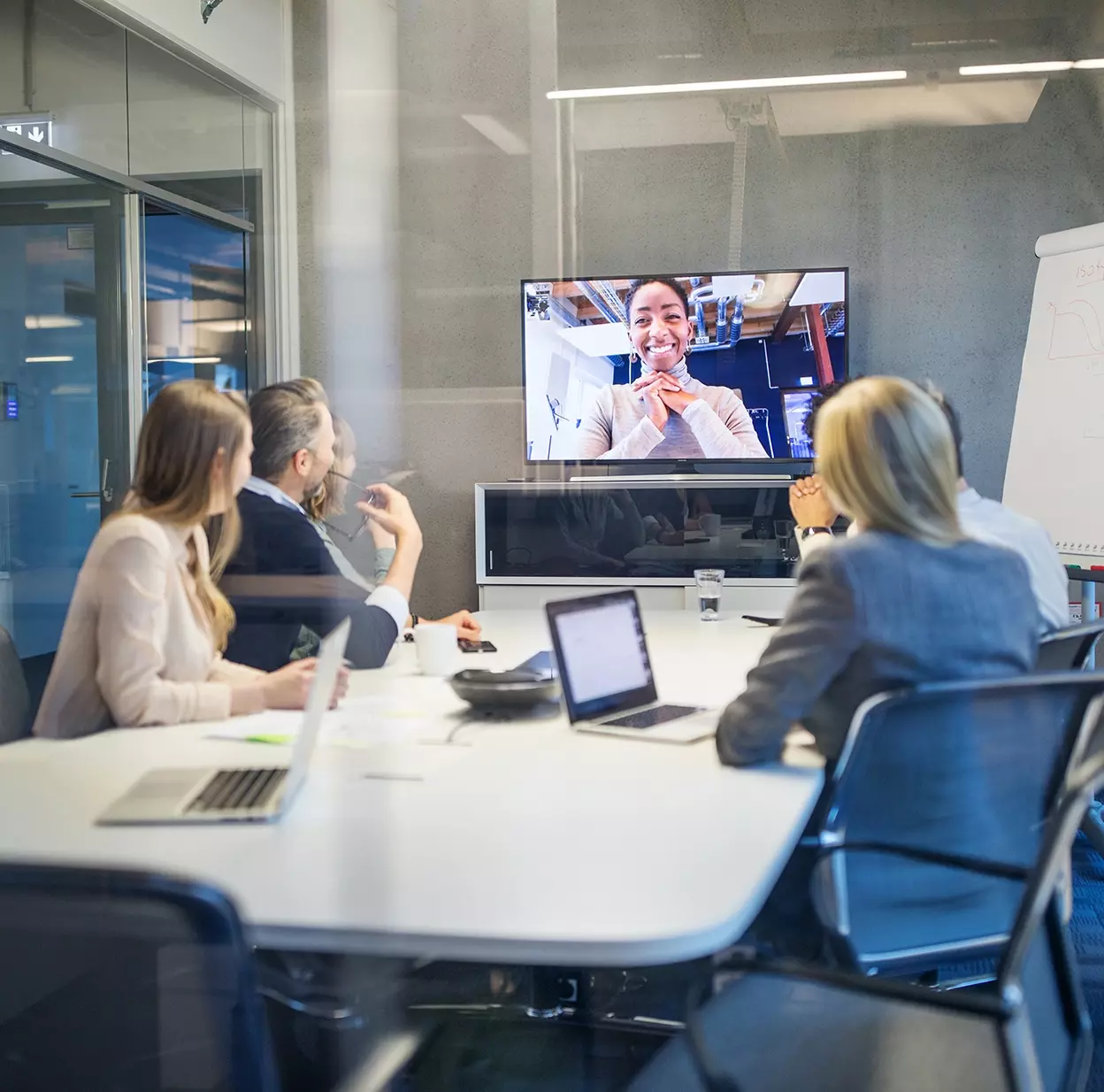 Office Workers in conference room and one on video call